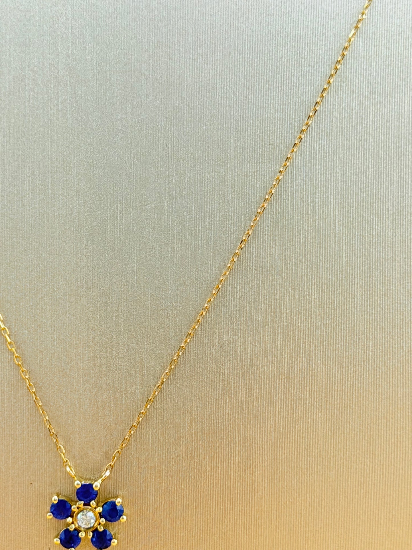 14kt gold necklace with a flower pendant, featuring a sapphire and natural diamond. 0.03 ct of natural diamonds and 0.36 ct of sapphire. Size 16”-18”